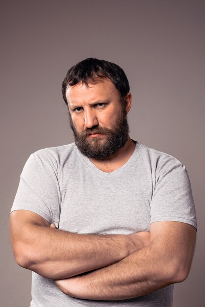 Angry bearded man in gray t-shirt looking at camera.