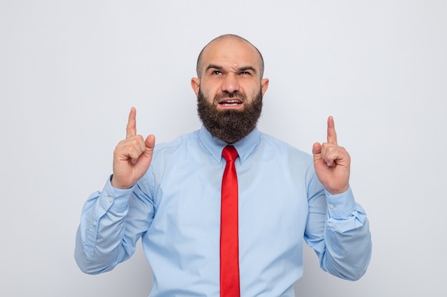 Angry bearded man in red tie and blue shirt looking up pointing with index fingers up