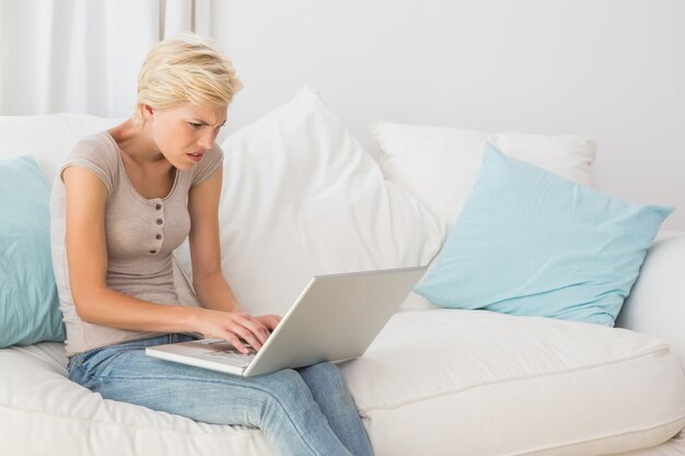 Angry blonde woman using her laptop  