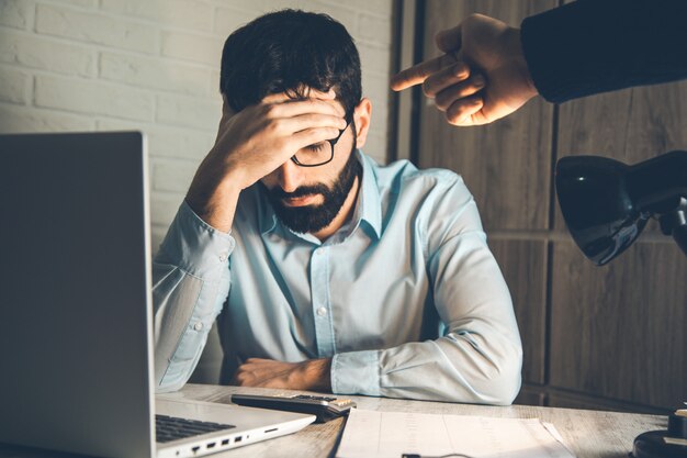 Angry boss with sad worker on desk