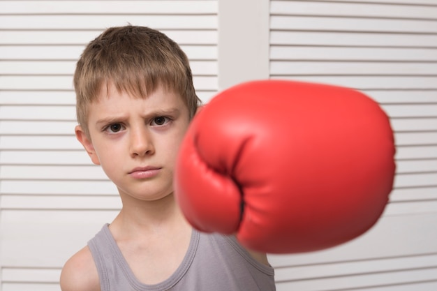 Angry boy in red boxing glove. Hit