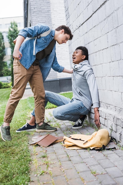 Angry boy in shirt bulling going to punch african american boy in hoodie