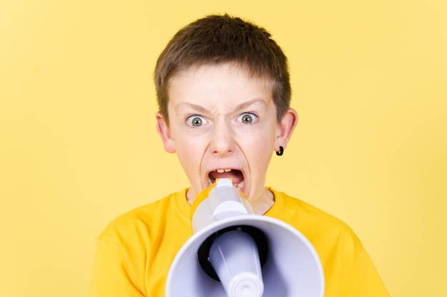 Photo angry boy shouting on megaphone and looking straight to camera