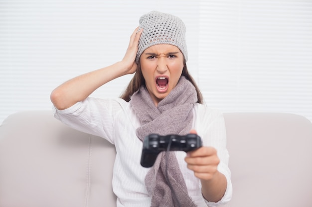 Angry brunette with winter hat on playing video games