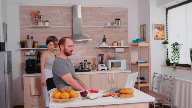 Uomo d'affari arrabbiato durante la colazione a causa di una brutta notizia. libero professionista infelice, stressato, frustrato furioso negativo e sconvolto in pigiama che urla durante il pasto mattutino a casa. problemi di lavoro