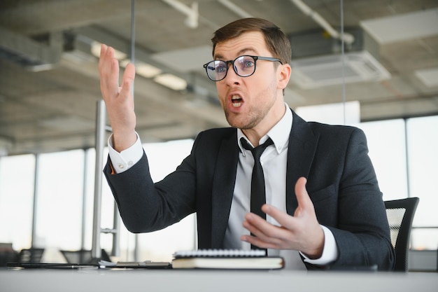 Angry businessman sitting at the table and screaming