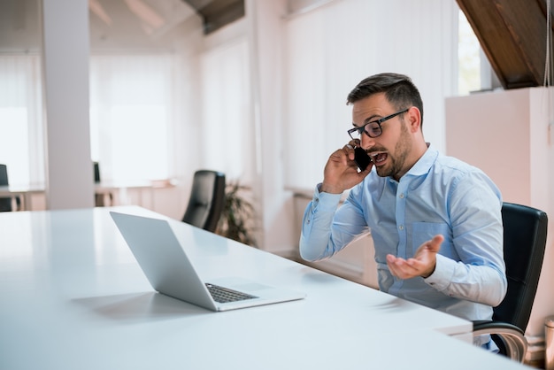 Photo angry businessman talking on the phone in office