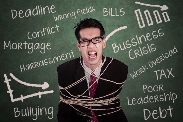 Angry businessman tied with rope in class