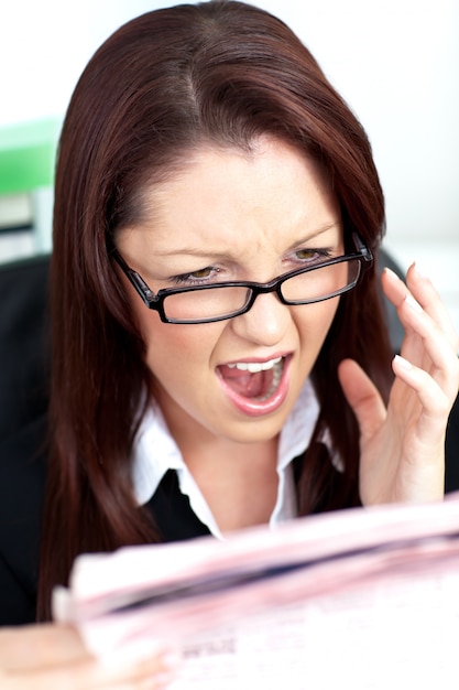 Angry businesswoman reading a newspaper