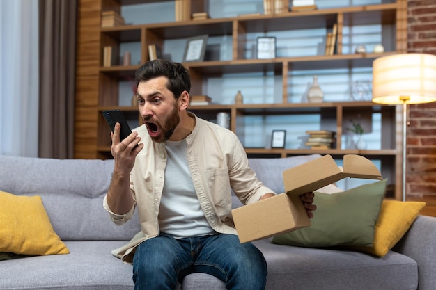 Angry cheated man at home with phone and boxed parcel received arguing on phone talking to online