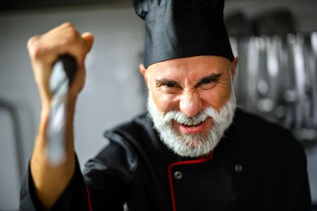 Photo angry chef in kitchen holding knife