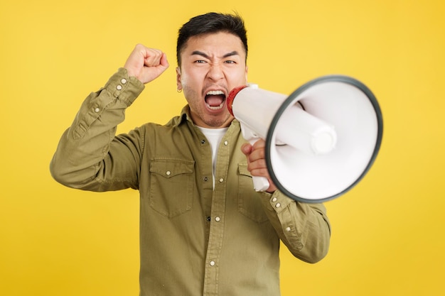 Angry chinese man shouting looking at camera using a loudspeaker