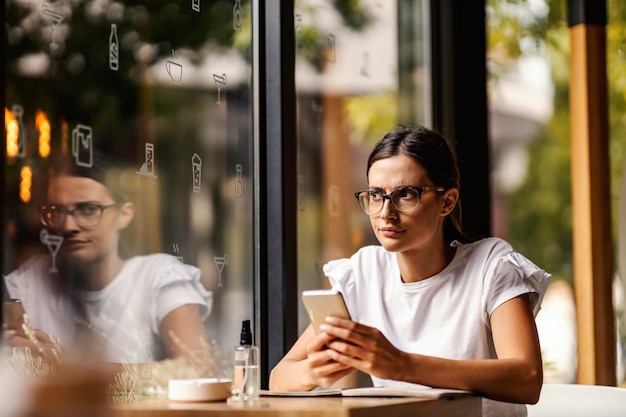 An angry college girl is sitting in a coffee shop and writing messages to someone