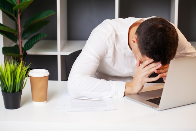 Angry company employee sits at a white table.