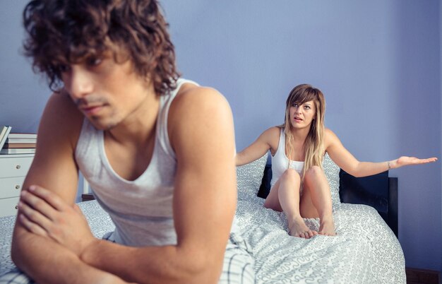 Photo angry couple sitting on bed at home