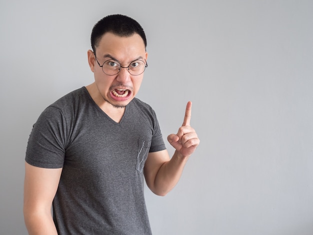 Angry and crazy asian man in black t-shirt and skinhead hair style.