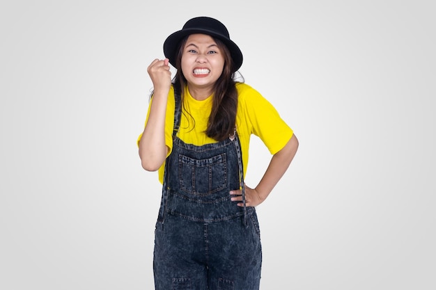 Foto ragazza asiatica carina arrabbiata in pugno di mano giallo con sfondo bianco