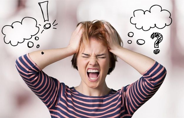 Angry depressed woman screaming and holding her head with hands