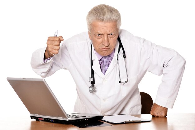 白い背景の上のラップトップで怒っている医者