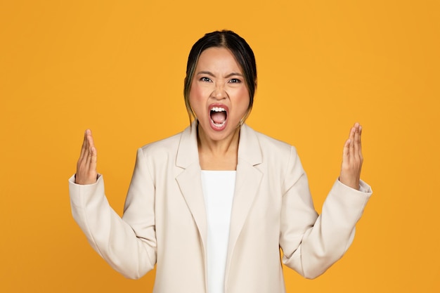 Angry excited crazy sad young asian woman in suit screaming freaking out