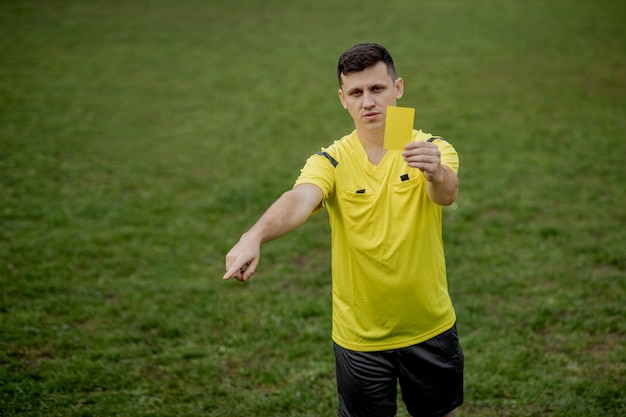 Angry football referee showing a yellow card and pointing with his hand on penalty