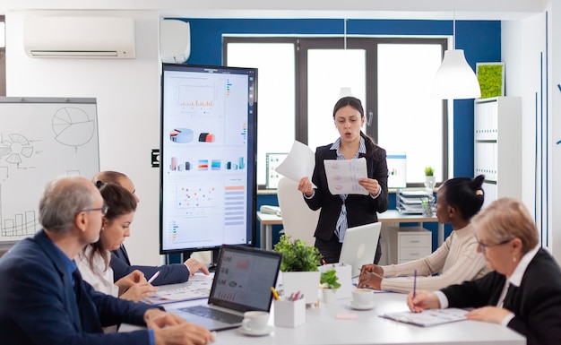 Angry furious manager woman screaming at diverse company workers in conference room looking at financial charts