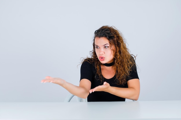 Angry girl is pointing left with hands on white background