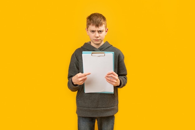 Злой мрачный мальчик в джинсах и толстовке с капюшоном держит белый лист бумаги и указывает на него пальцем Результаты теста концепция оценки студентов Копирование пространства