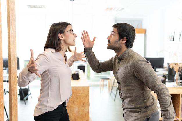 Angry hispanic coworkers discussing and arguing at the office