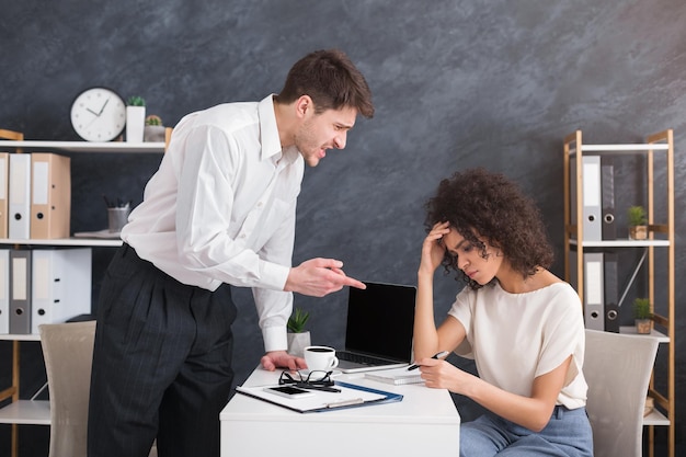 Angry irate boss yelling and shouting at his secretary employee in office