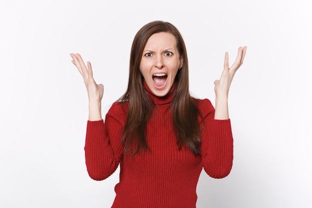 Angry irritated young brunette woman girl in casual red clothes posing isolated on white background studio portrait. People lifestyle concept. Mock up copy space. Spreading hands, screaming swearing.