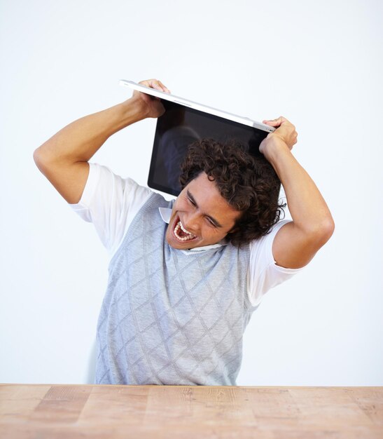 Angry laptop and frustrated businessman smash his computer due to stress isolated in a white studio background Anxiety depression and male employee destroy equipment due to 404 glitch or error