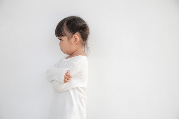 Bambina arrabbiata su sfondo bianco, segno e concetto di gesto