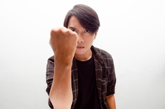 Angry, mad, frustrated and furious asian man raising his fist\
looking for fight.