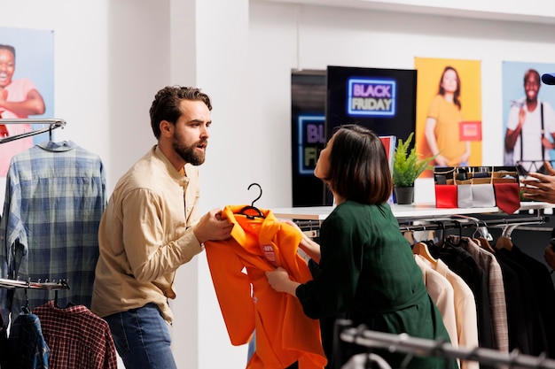 화난 남자와 여자가 옷 가게에서 싸우고 있다. 공격적인 다양한 사람들이 블랙 프라이데이 판매 기간 동안 쇼핑하는 동안 할인된 가격으로 마지막 옷 품목을 놓고 싸우고 있다.