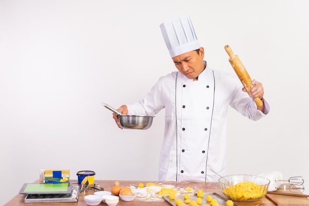 Angry male chef holding bowl of dough and rolling pin