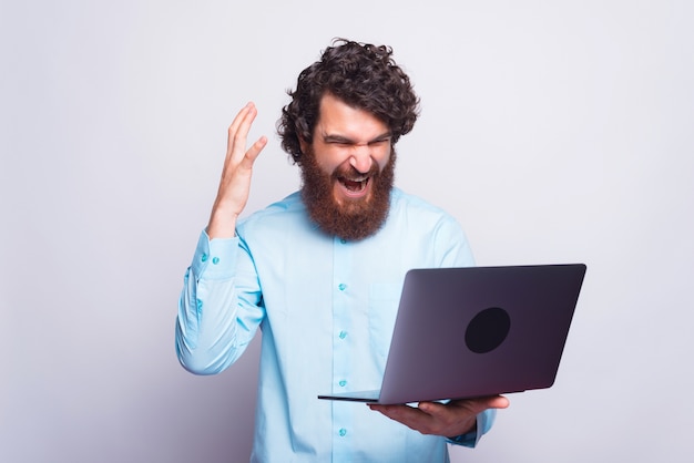 Uomo arrabbiato in camicia blu che ha problemi al lavoro, uomo che grida al computer portatile