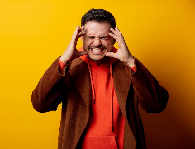 Photo angry man in coat on yellow wall