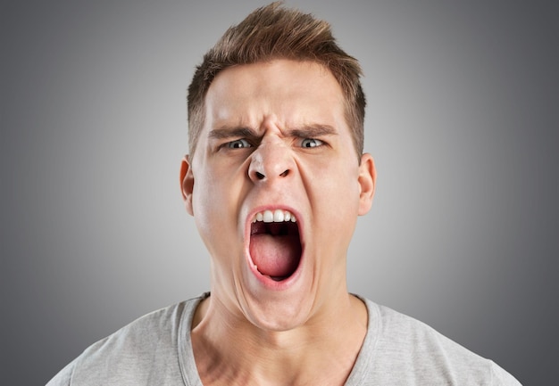 Angry man screaming on light background