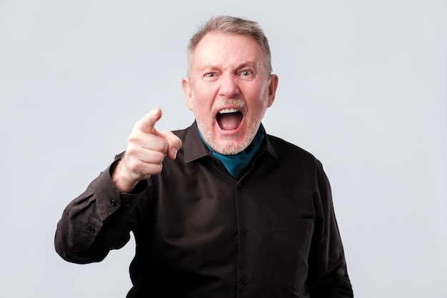 Angry man screaming pointing index finger at you