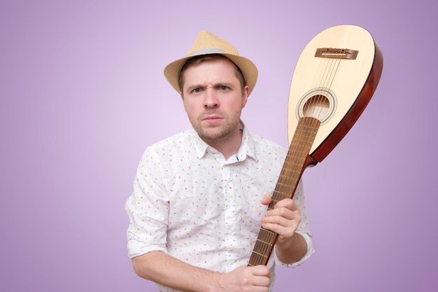 Angry man in summer hat hitting guitar