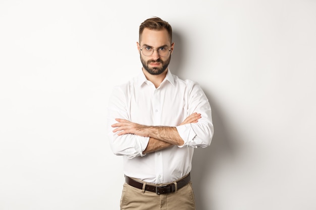 Angry manager looking disappointed, cross arms on chest and frowning displeased, standing over white background