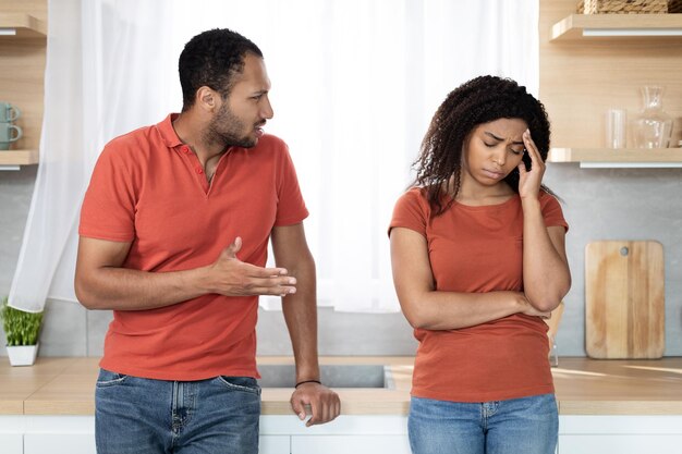 Photo angry millennial black male scolding of offended wife suffering from pressure and stress in kitchen interior