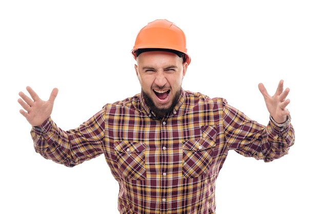 Foto un lavoratore arrabbiato e nervoso con un casco arancione sta parlando ad alta voce al telefono, gridando al telefono. sfondo bianco isolato