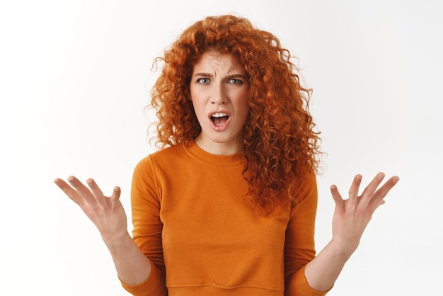 Angry outraged attractive stylish redhead woman raising hands in dismay complaining stare frustrated and furious bothered bad service shouting at manager stand white background disappointed