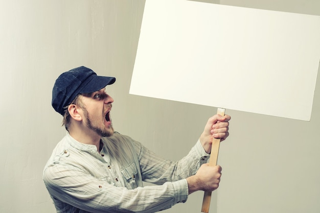 Foto operaio di protesta arrabbiato con segno di protesta in bianco.