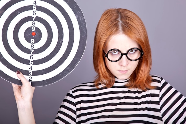 Photo angry red-haired girl with dartboard.