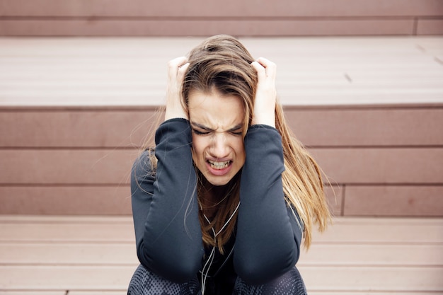 Foto seduta triste arrabbiata della giovane donna all'aperto