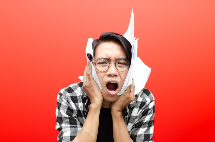 Photo 빨간 배경에 격리된 종이 작업을 들고 있는 아시아 남학생이나 노동자에게 화가 나고 지쳤습니다.