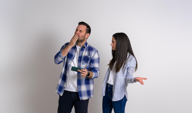 Angry woman gesturing and looking at ecstatic gamer man blowing kiss while playing video game